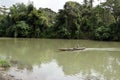 Man rowing a small tiny passenger boat on murky river using paddle