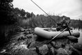 A man on rubber boat catching fish on the lake. Black and white photo. Royalty Free Stock Photo