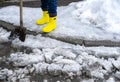 man in rubber foam boots cleaning the track from old snow. He shovels off dirty wet snow with a shovel so that it melts Royalty Free Stock Photo