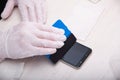 man in rubber gloves glues a protective glass to a smartphone using a special palstic spatula with a soft nozzle