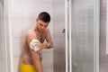 Man rubbing himself a foam sponge bath in shower cabin