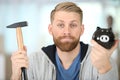 man with rueful expression holding hammer and piggybank Royalty Free Stock Photo