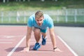 Man runner on start position at stadium. Runner in start pose on running surface. Man run outdoor at running track