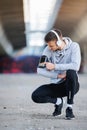 Man runner taking a break after intensive training outdoors, listening music on his mobile smart phone Royalty Free Stock Photo