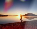 Man running on beach against backdrop of a beautiful sunset. Sand of mountain lake