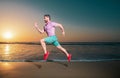 Man running on the beach at sunset. Sport and healthy lifestyle. Athlete running around the beach line near the sea. Fit Royalty Free Stock Photo