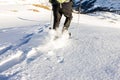 Man running downhill through deep snow with snoeshoes and hiking sticks.