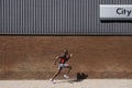 Man running past brick wall with City written on it Royalty Free Stock Photo