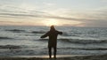 Man runs on the evening beach and throws sand. Male enjoying the nature landscape on the shore of the sea with waves.