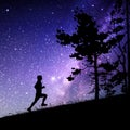 Man runs uphill at night. Male runner silhouette. Milky Way and stars