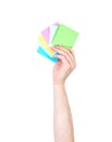 Man's arm raised holding a set of colorful notepads, isolated on white background. Royalty Free Stock Photo