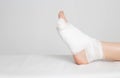 Man`s bandaged foot with little finger on a white background. The concept of a fracture of the little finger on the leg