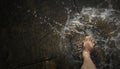 Man`s barefoot jumps into the glassy puddle on the empty road after hard rainfall. Crystal clear water splashes with the high-spee Royalty Free Stock Photo