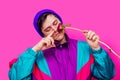 Man in 90s clothes sniffs blossom peony flower on pink background.