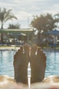 Man's feet on the background of a swimming pool. man relaxing by the pool, men's feet on the pool background. toned. vertical