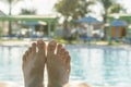 Man's feet on the background of a swimming pool. man relaxing by the pool, men's feet on the pool background. toned