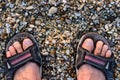 Man`s Feet in Sandals Standing On The Rocky Beach Royalty Free Stock Photo