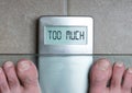 Man`s feet on weight scale - Too much