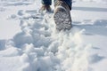 A man's feet in winter shoes take a step on a snowy road on a winter walk. Generative AI