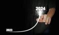 A man`s finger draws an upwards curved line from 2023 to 2024. New Year, Christmas, start-up, new business, setting a personal