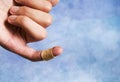 A man's finger tied with a medical band aid on a blue background Royalty Free Stock Photo