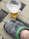 Man`s foot in rubber slippers. Covered with salt after swimming in a saltwater pool. Nearby is a glass of beer Royalty Free Stock Photo