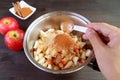 Man`s hand adding a spoon of ground cinnamon into the pot of diced apples for making apple compote Royalty Free Stock Photo