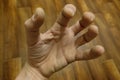 A man`s hand against a parquet background. The fingers are bent in a strange way. Royalty Free Stock Photo