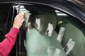 The manÃ¢â¬â¢s hand applies a degreasing cleaner with a yellow sponge to the side window of the car to apply a protective nano Royalty Free Stock Photo