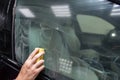 The manÃ¢â¬â¢s hand applies a degreasing cleaner with a yellow sponge to the side window of the car to apply a protective nano Royalty Free Stock Photo