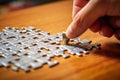 A man\'s hand assembles a puzzle on a table.
