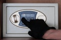 A man in black gloves enters a security code on the safe. The thief hacks electronic safe in the office or at home. Theft. Royalty Free Stock Photo