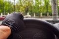 A man`s hand in a black medical glove on the steering wheel of a car. Anti-virus security concept