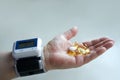 A man`s hand with a blood pressure monitor on his wrist and pills in the palm of his hand. Selective focus Royalty Free Stock Photo