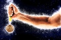 Man`s hand in a blue fire is holding gold medal. Winner in a competition. Royalty Free Stock Photo