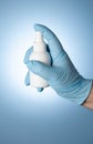 A man`s hand in a blue medical glove holds a white plastic spray from covid-19