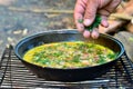 A man`s hand in a blurry motion sprinkles dill greens on an open-air fried egg in a frying pan Royalty Free Stock Photo