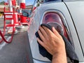 Man`s hand cleaning the car with black microfiber cloth. Hand wipe down surface of car Royalty Free Stock Photo