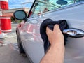 Man`s hand cleaning the car with black microfiber cloth. Hand wipe down surface of car Royalty Free Stock Photo