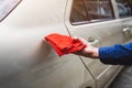 Man`s hand cleaning car & drying vehicle with microfiber cloth. Hand wipe down paint surface of shiny blue sedan after polishing Royalty Free Stock Photo