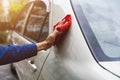 Man`s hand cleaning car & drying vehicle with microfiber cloth. Hand wipe down paint surface of shiny blue sedan after polishing Royalty Free Stock Photo