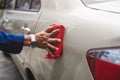 Man`s hand cleaning car & drying vehicle with microfiber cloth. Hand wipe down paint surface of shiny blue sedan after polishing Royalty Free Stock Photo