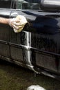 Man`s hand clears the fence from the car door with a sponge with plenty of foam. Royalty Free Stock Photo