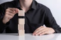 Man`s hand completing set of 4 stacked wooden cubes., man build a tower by using four blank wooden cube on table. Mockup for lette