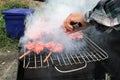 Man`s hand is cooking `Pork and chicken grilled` Thai street food in Bangkok Thailand, Whole grilled chicken skewered on a grill t Royalty Free Stock Photo