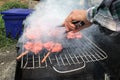 Man`s hand is cooking `Pork and chicken grilled` Thai street food in Bangkok Thailand, Whole grilled chicken skewered on a grill t Royalty Free Stock Photo