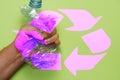 man's hand crushing a plastic bottle with pink recycling symbol. recycling concept. plastic free. flat lay Royalty Free Stock Photo