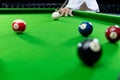 Man`s hand and Cue arm playing snooker game or preparing aiming to shoot pool balls on a green billiard table Royalty Free Stock Photo