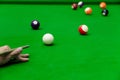 Man`s hand and Cue arm playing snooker game or preparing aiming to shoot pool balls on a green billiard table Royalty Free Stock Photo