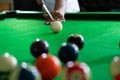 Man`s hand and Cue arm playing snooker game or preparing aiming to shoot pool balls on a green billiard table Royalty Free Stock Photo